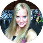 Smiling woman with long blonde hair in a kitchen with black and white tiles.